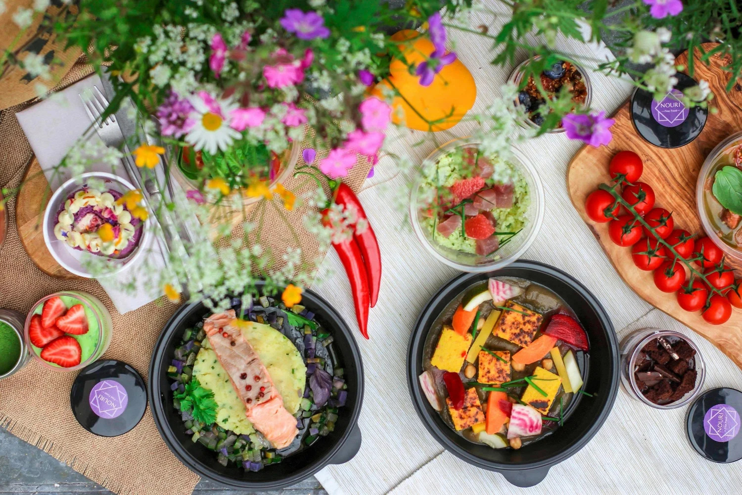 A table spread with salads, grain bowls and fresh flowers