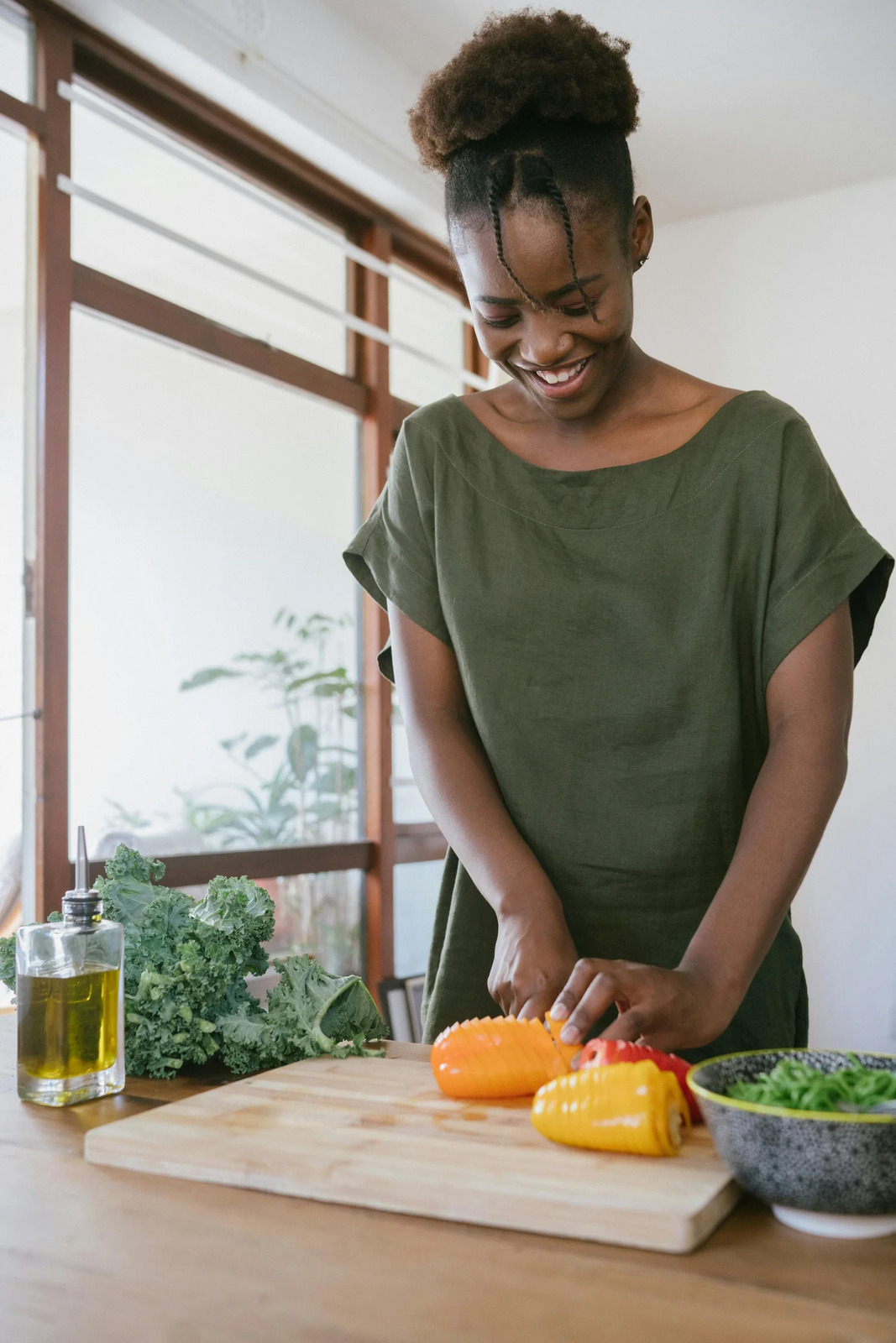 A smiling woman chopping peppers at her kitchen counter