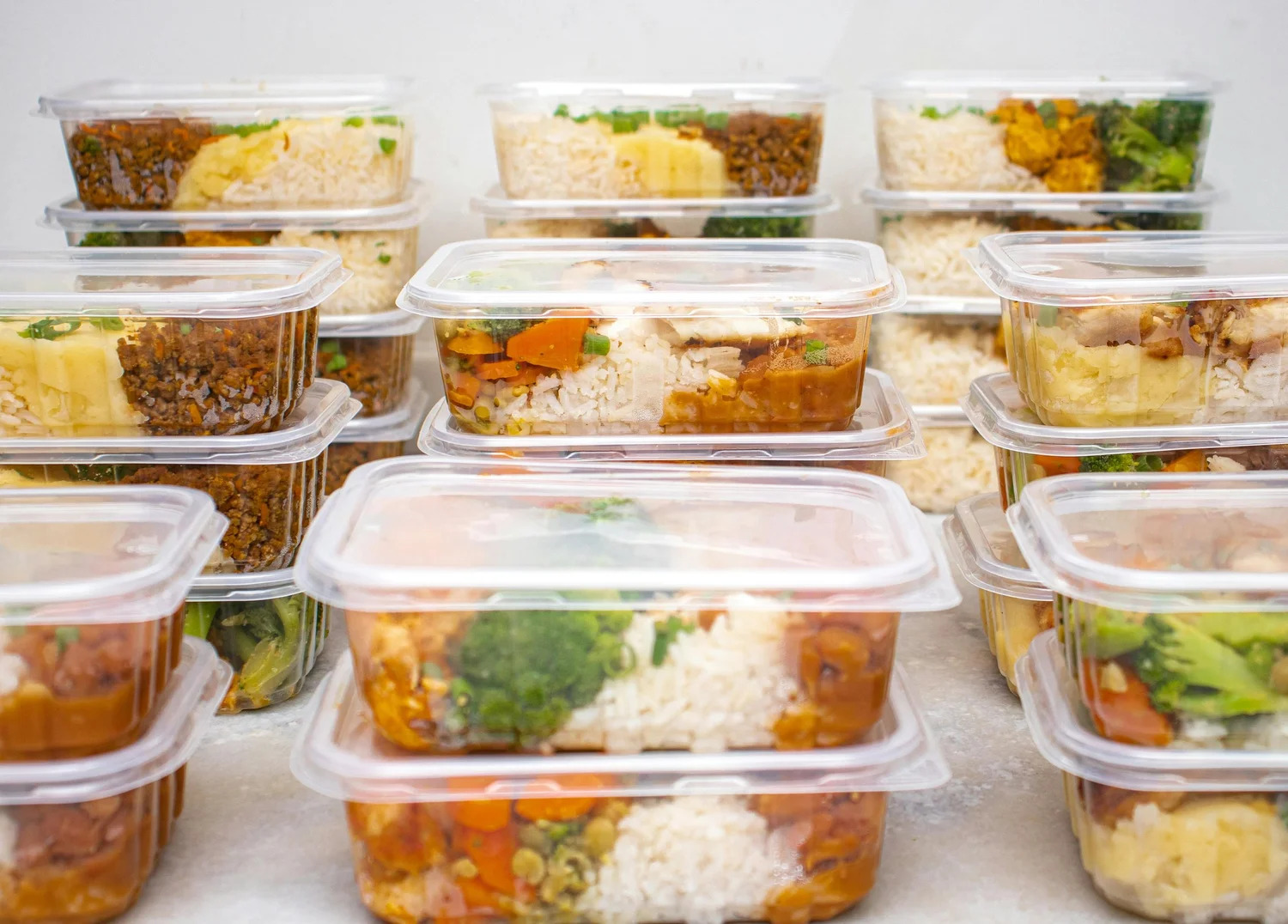 Stacked containers of prepared meals with rice and vegetables