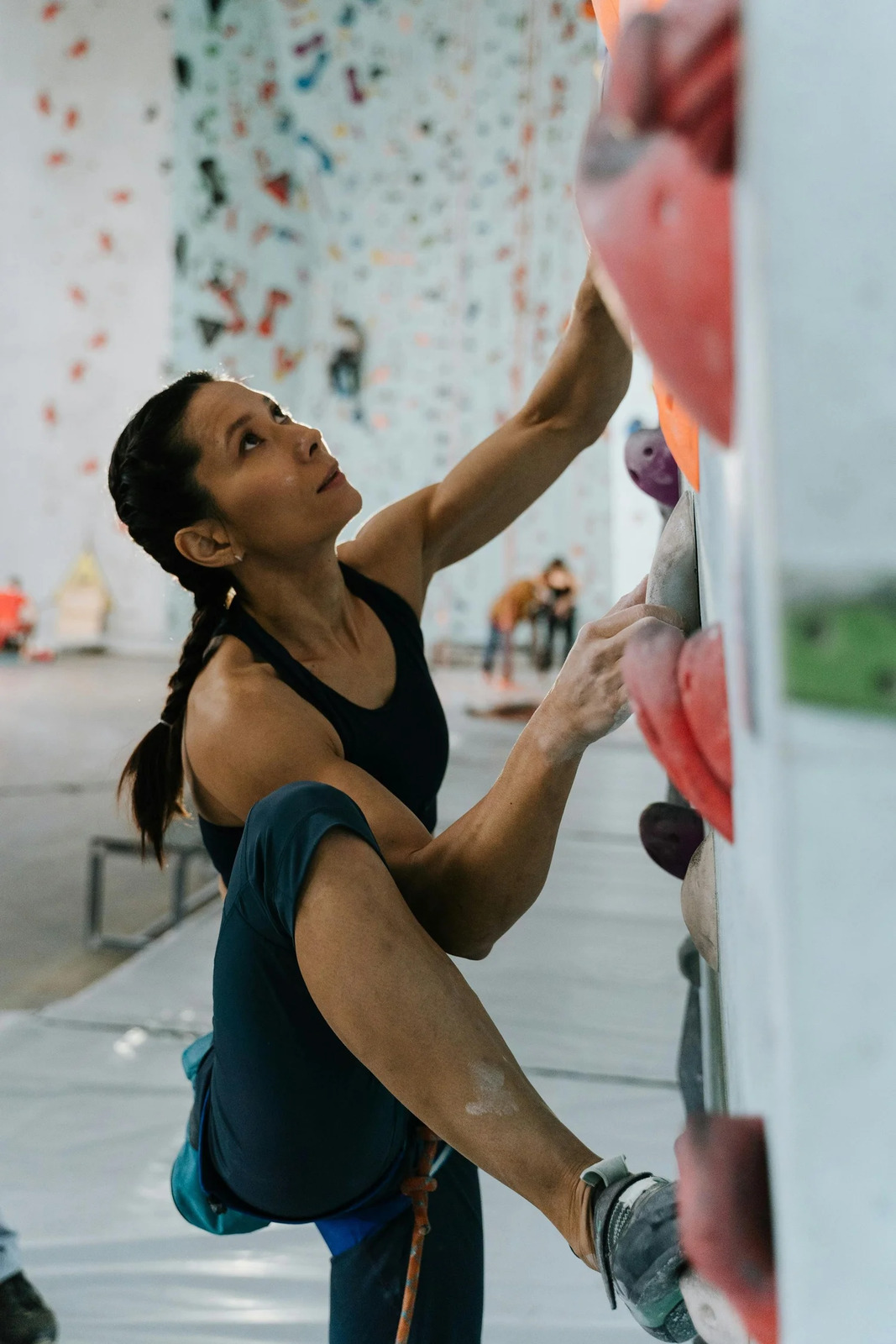 A woman climbing an indoor bouldering wall