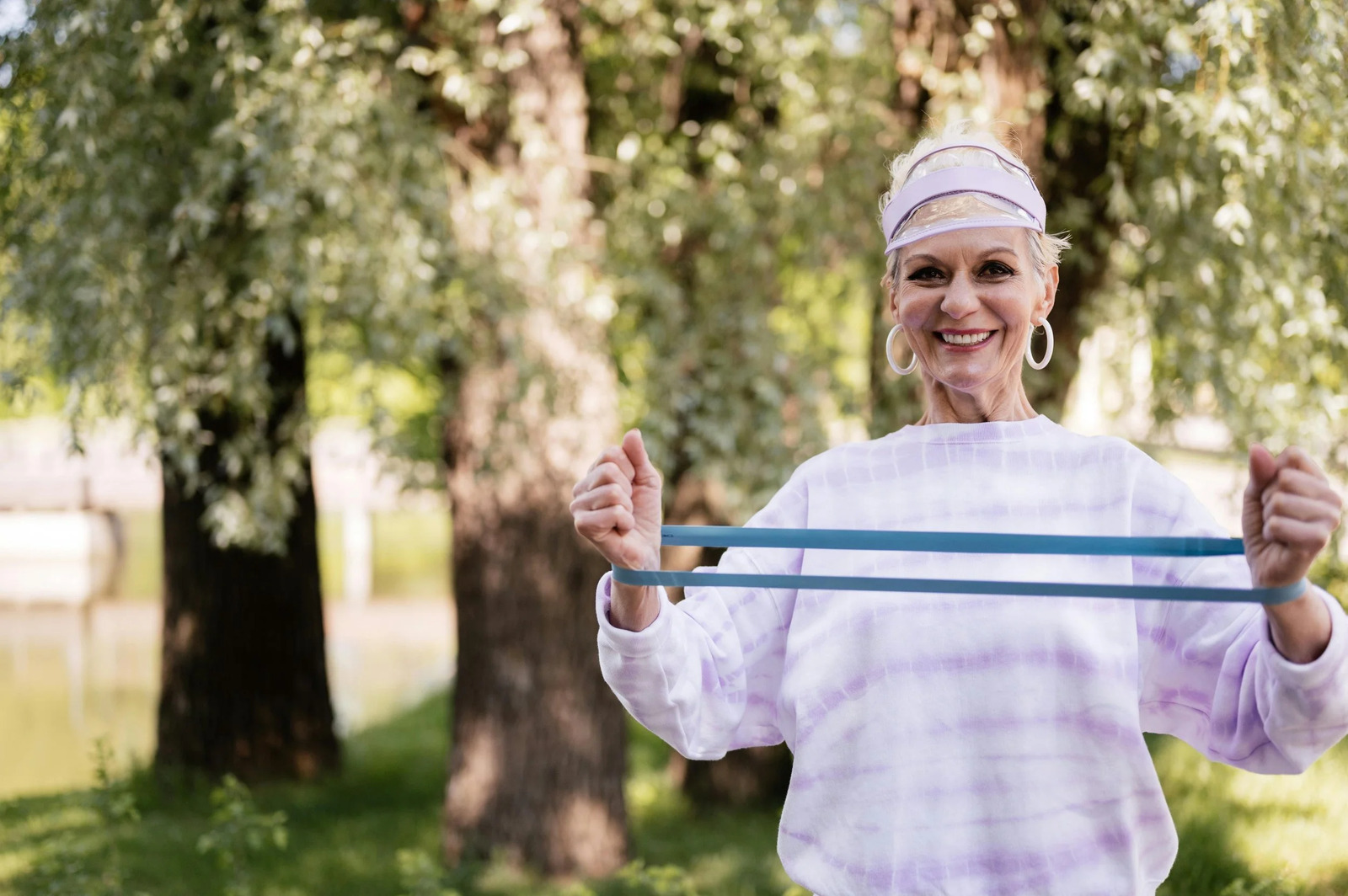 An older woman exercising outdoors with a resistance band