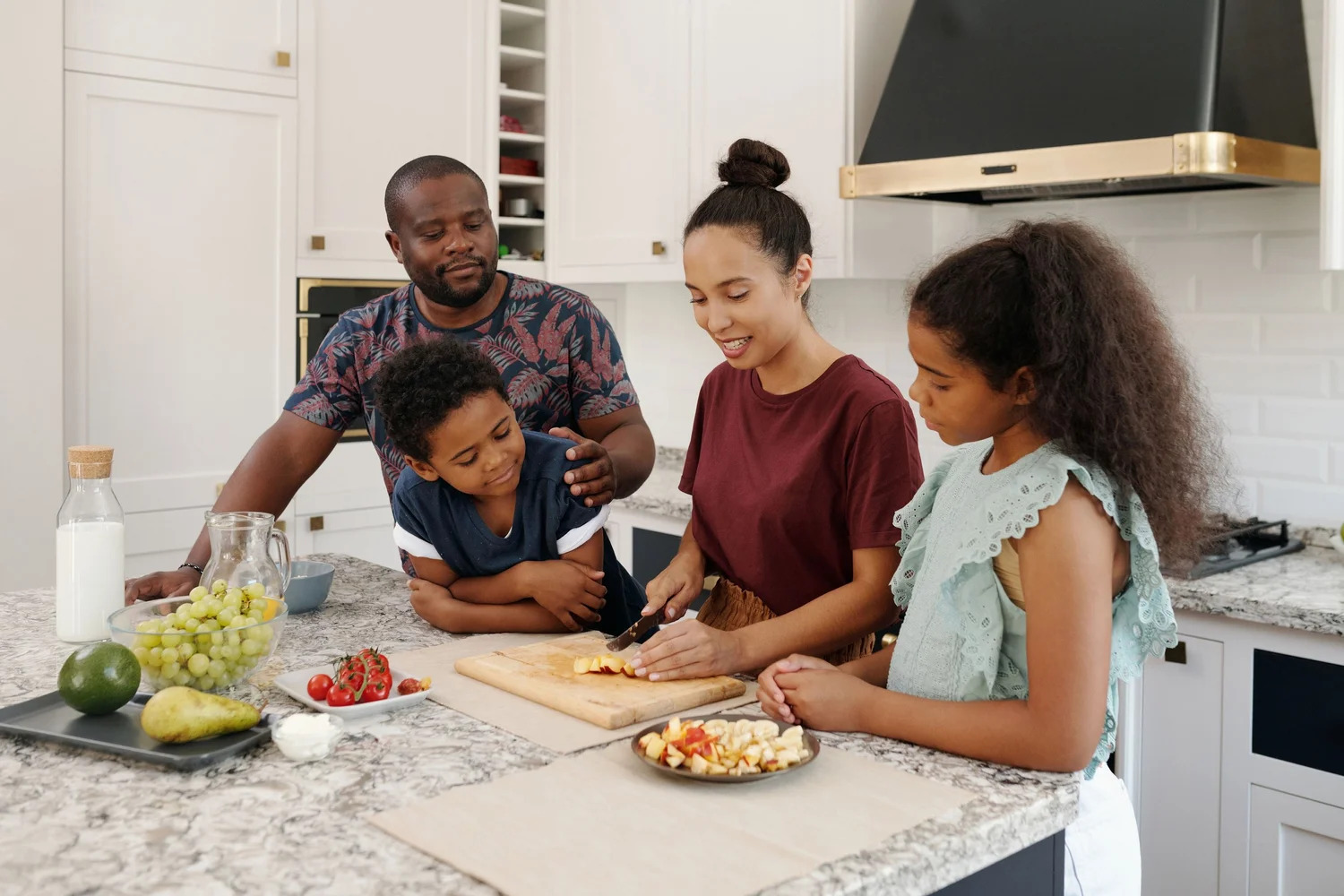 Parents and two children cooking together in a home kitchen