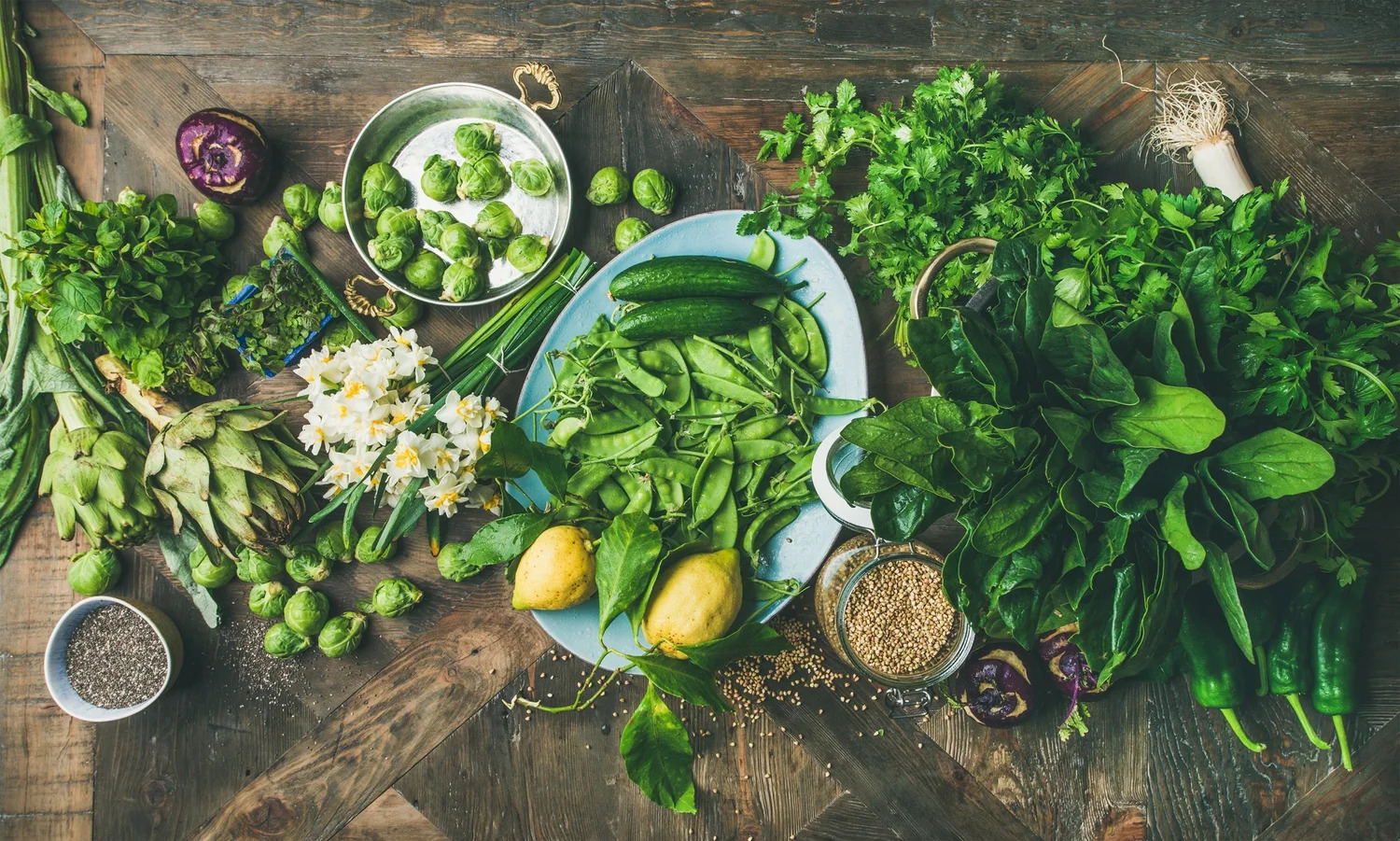 Fresh herbs, greens and spring vegetables on a rustic table