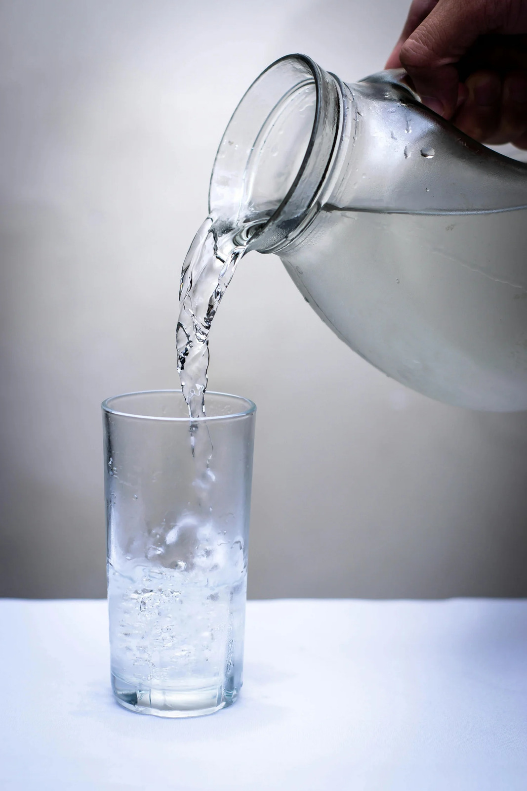Water being poured from a glass pitcher into a tumbler