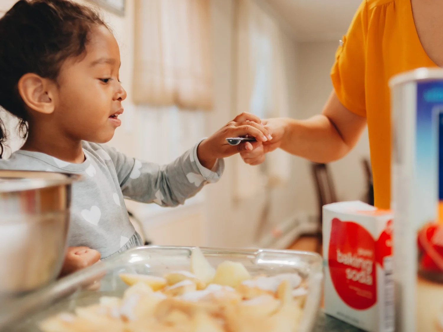 A young girl helping an adult prepare food in the kitchen