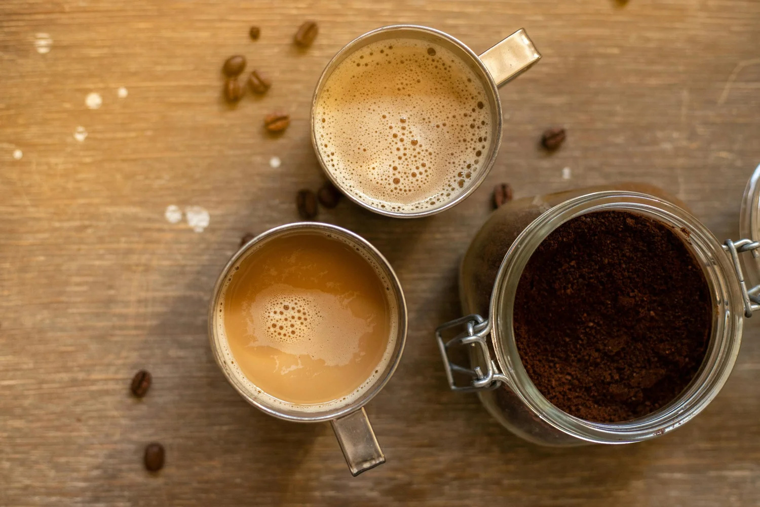Cups of coffee beside a jar of ground coffee