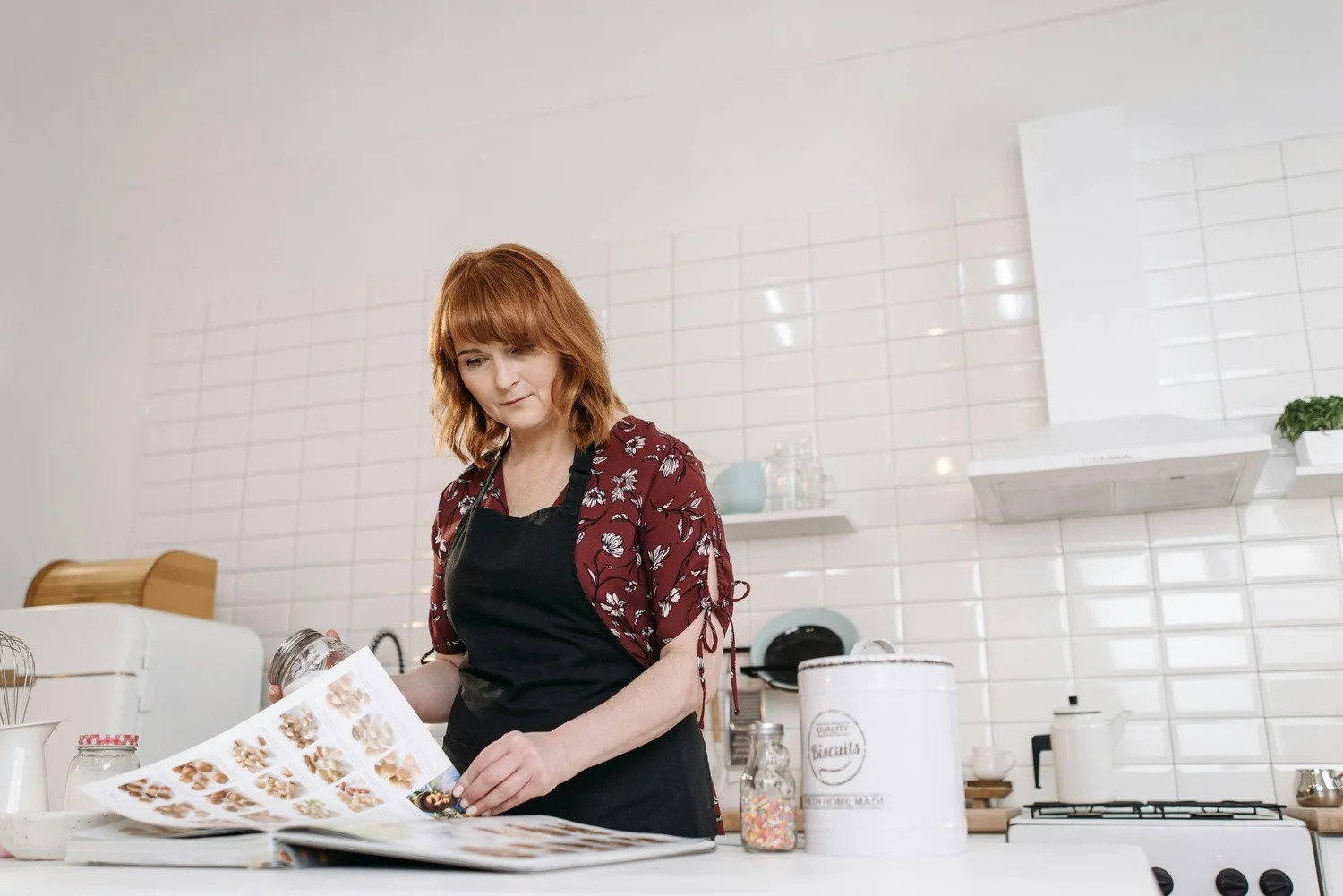 A woman reading a recipe book at her kitchen counter