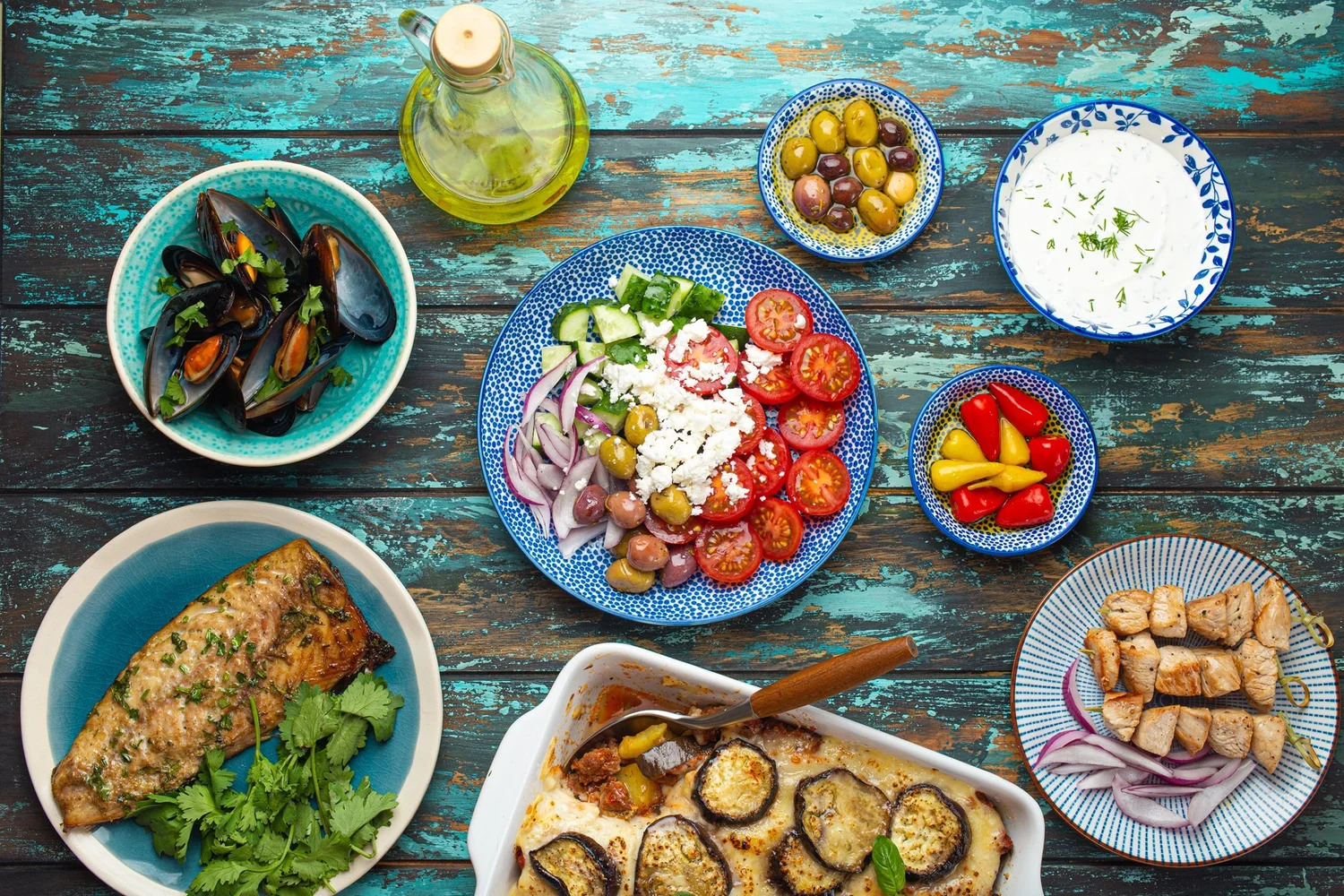 An overhead spread of Greek dishes including mussels, salad, fish and tzatziki