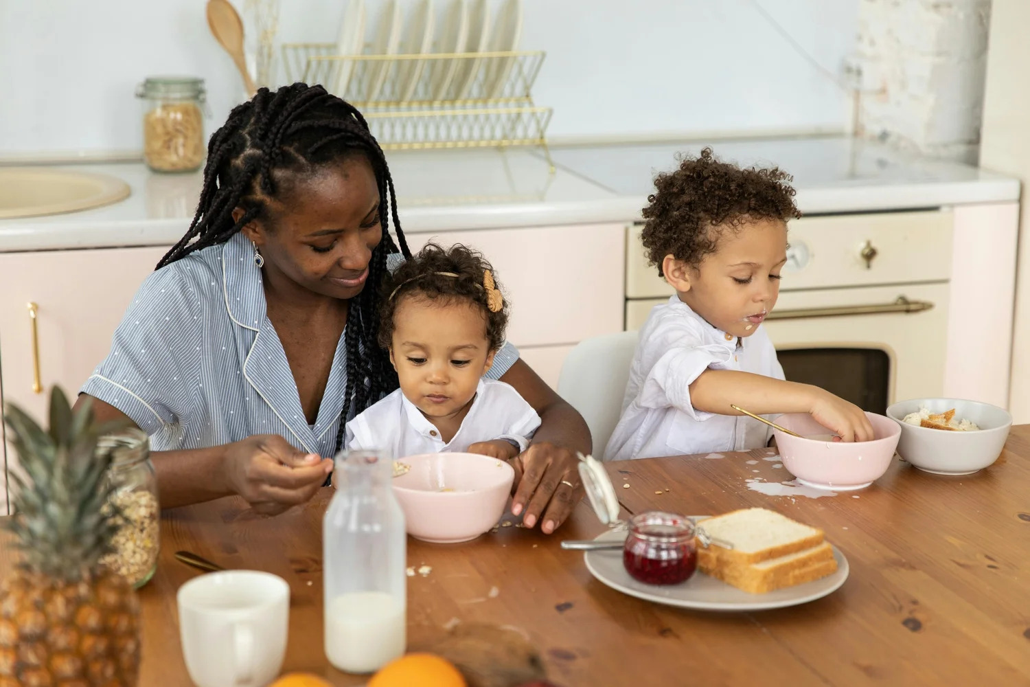 A mother and two young children eating breakfast at the kitchen table