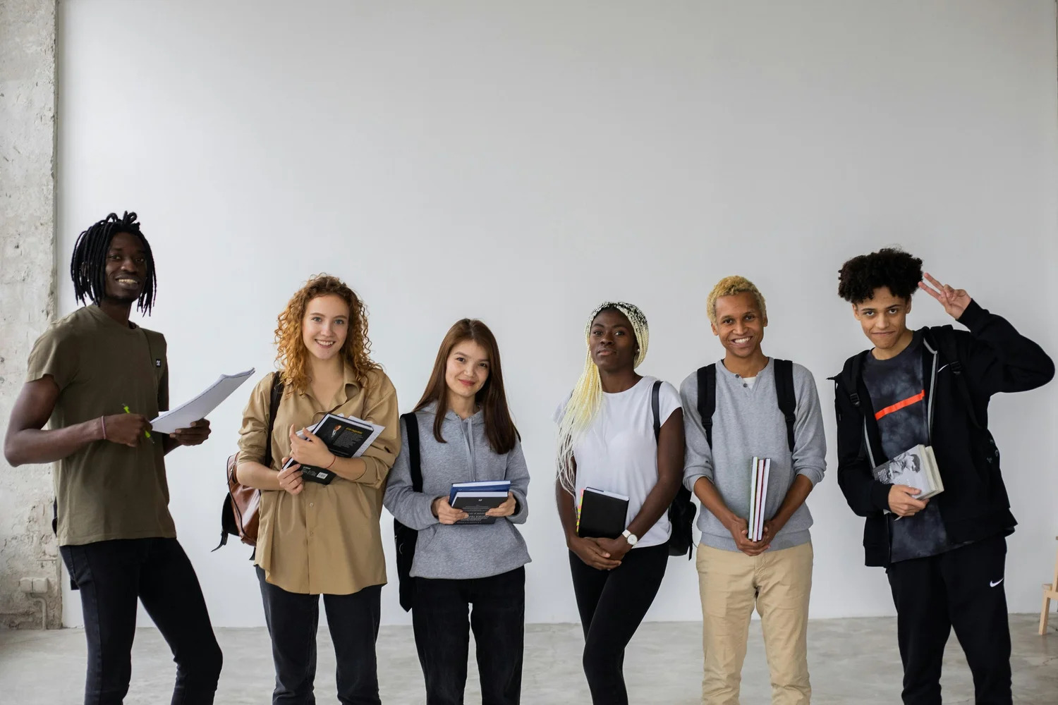 A group of teenagers with backpacks and notebooks standing together