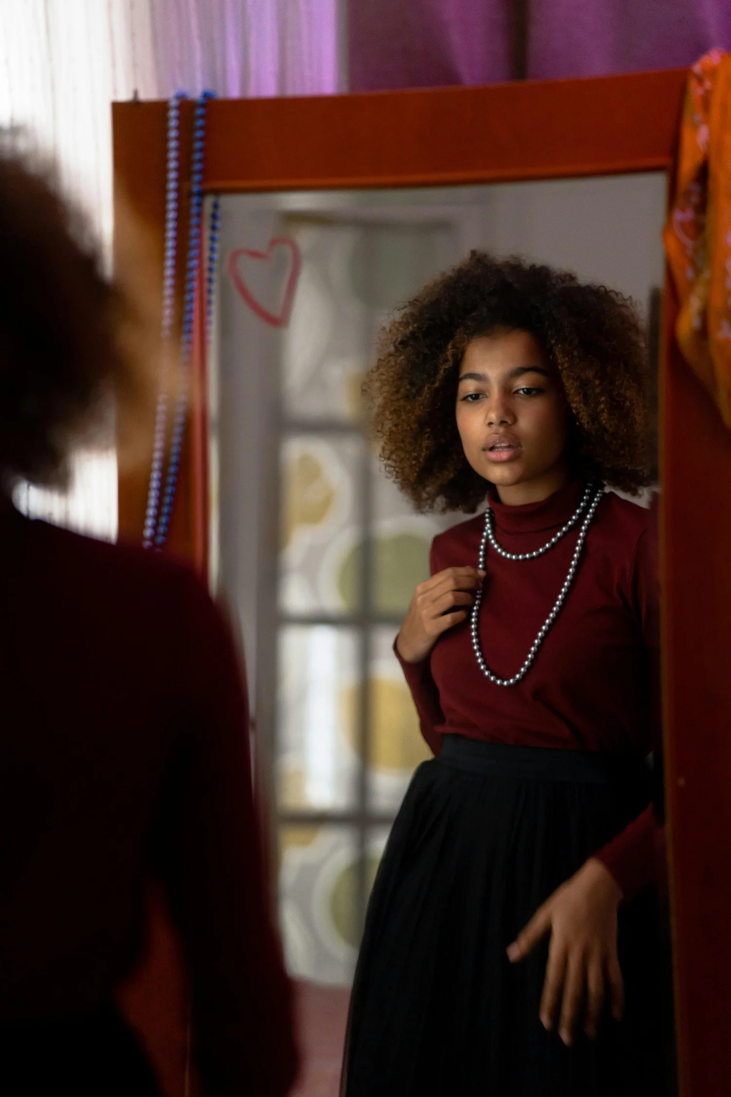 A teenage girl looking at her reflection in a mirror