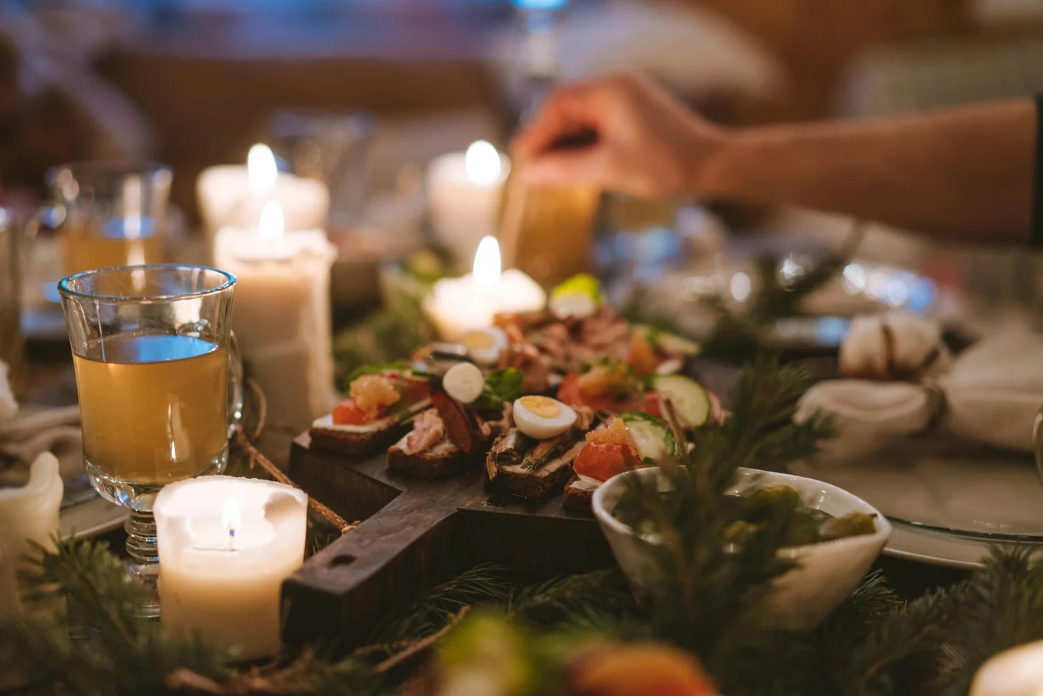 A candlelit holiday table set with dishes and greenery