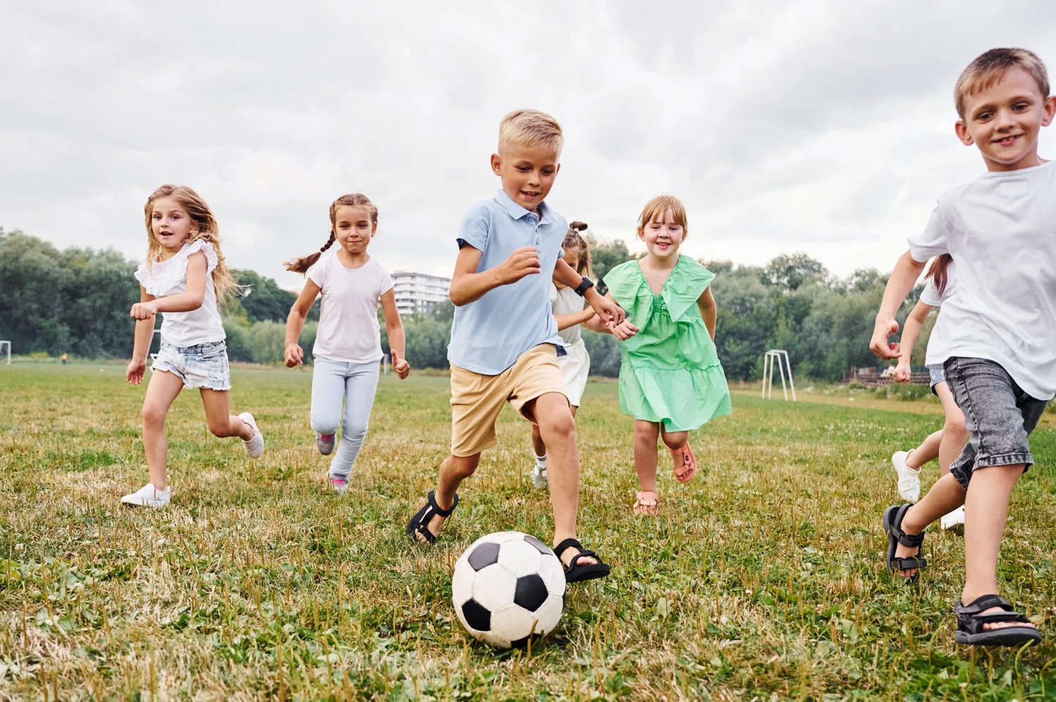 Children running after a soccer ball on a grass field