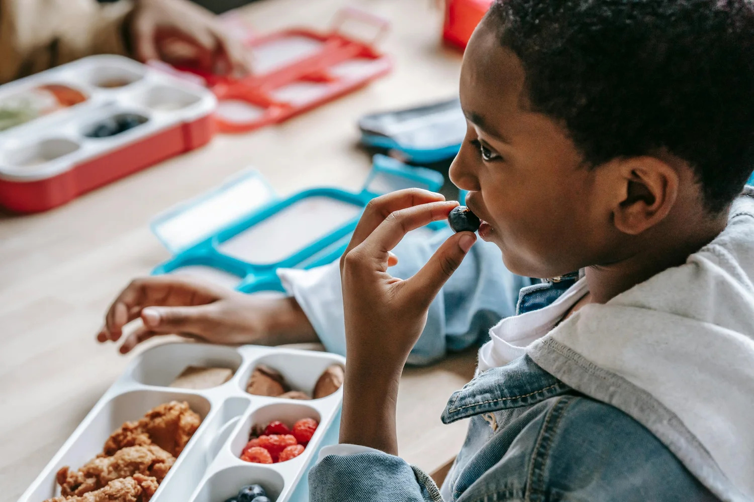 A boy eating from a packed lunchbox at a table
