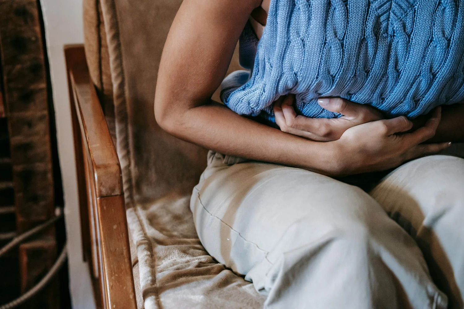 A person seated in a chair holding their stomach