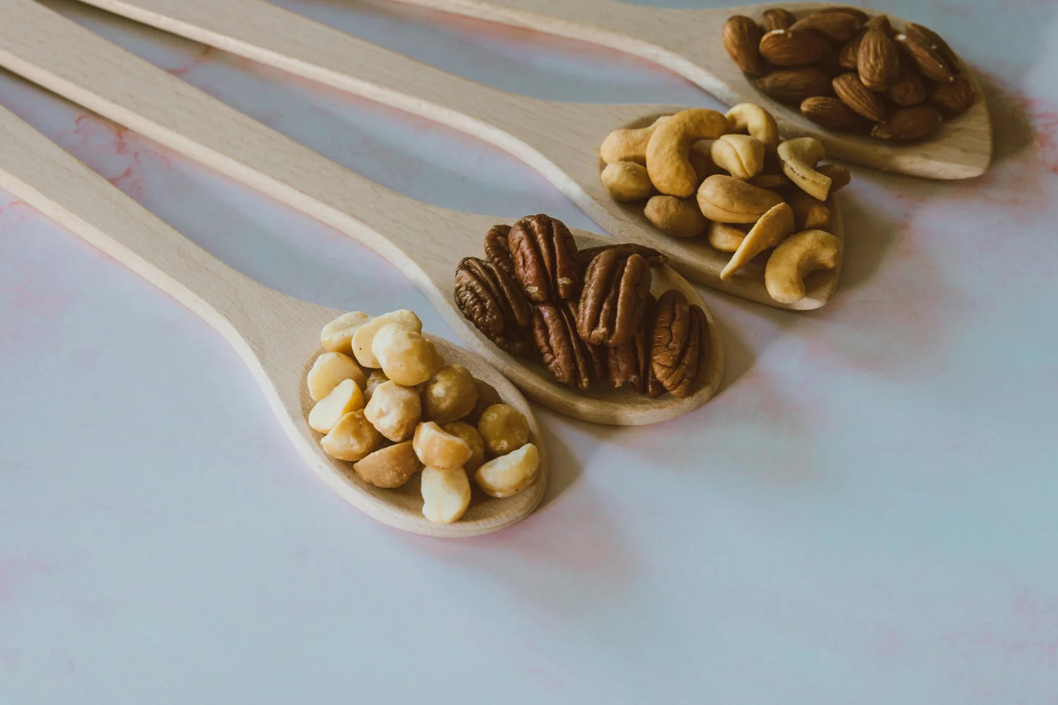 Wooden spoons holding cashews, pecans and other nuts
