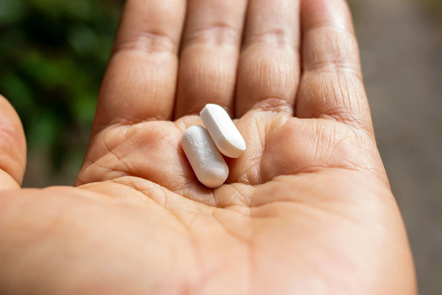 An open hand holding two white capsules