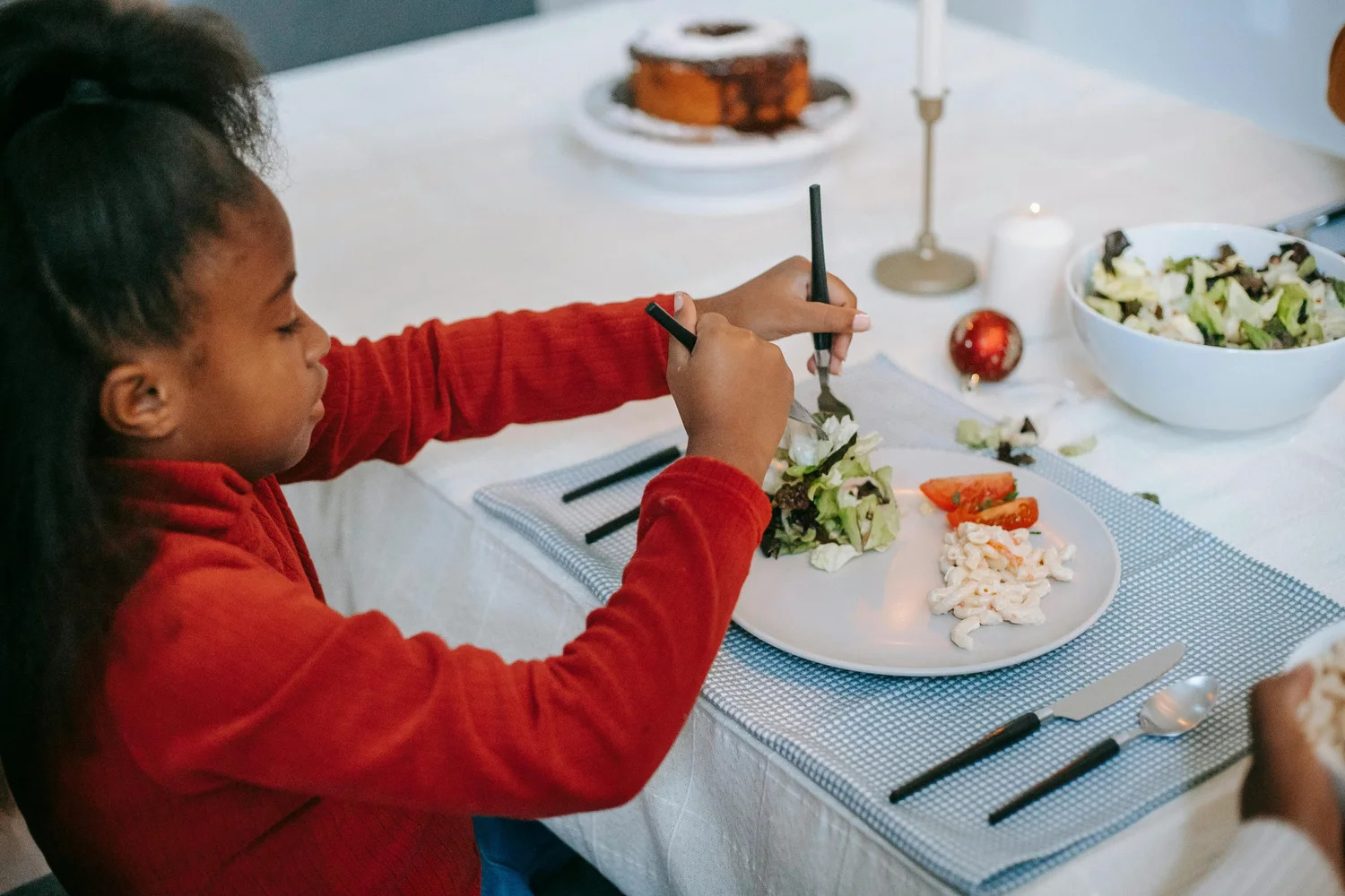 A girl eating a plate of vegetables at a set table