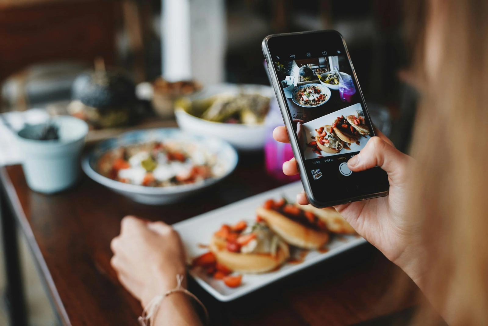 A person photographing a restaurant meal with a smartphone