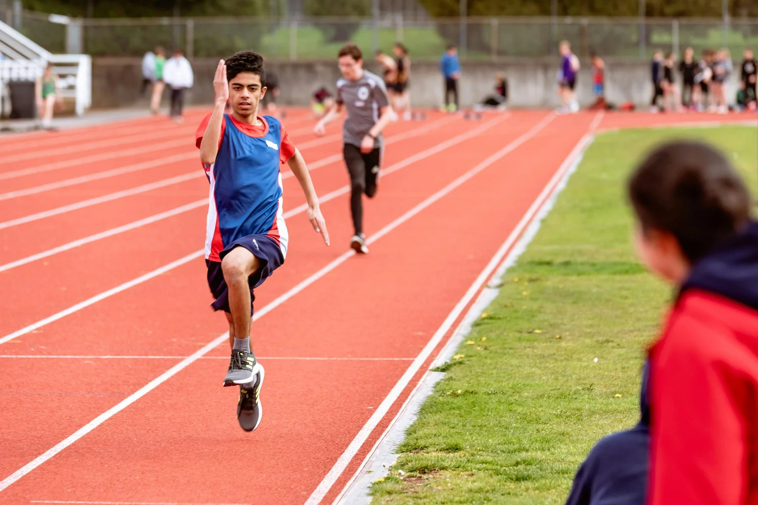 A teenage runner sprinting on a track during a race