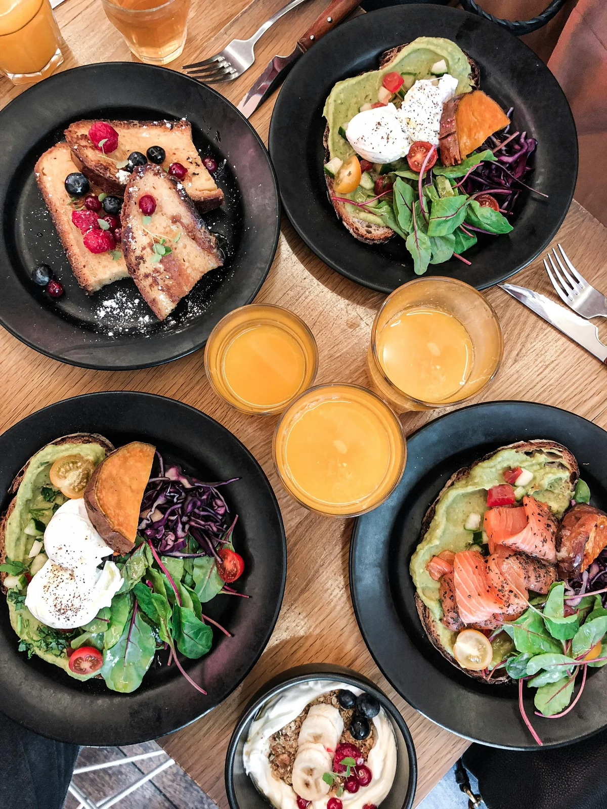 Overhead view of brunch plates with salads, eggs and orange juice