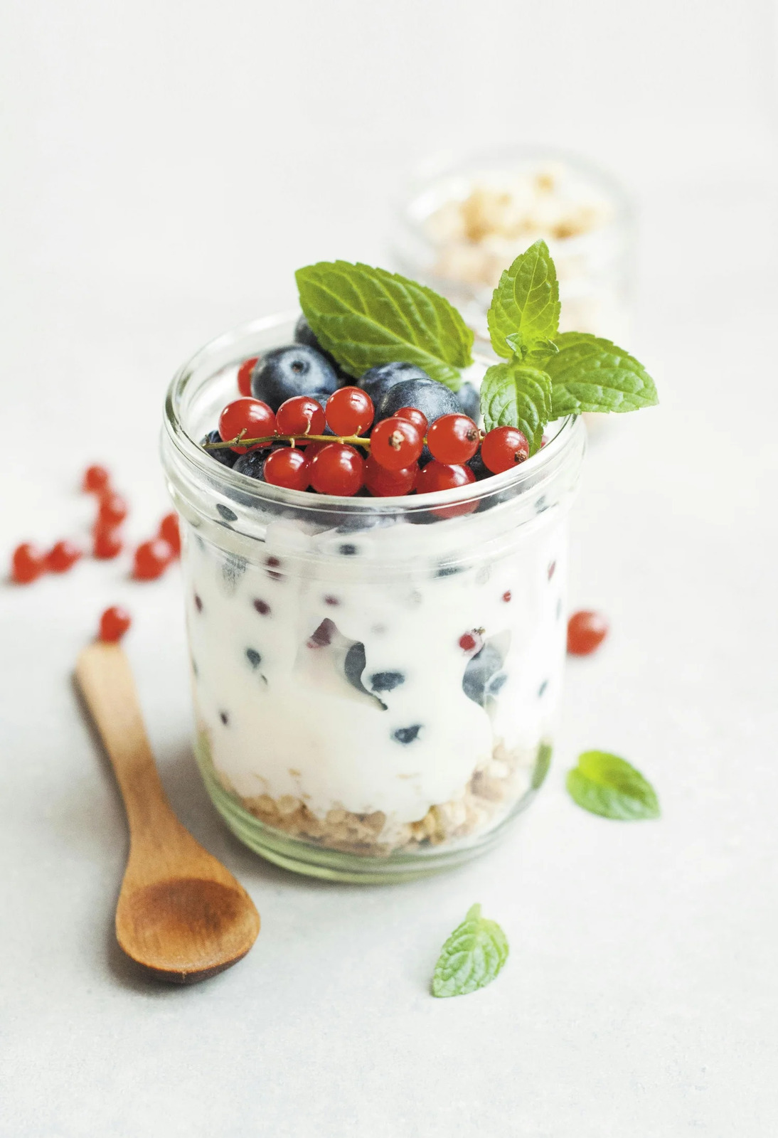 A jar of yogurt layered with granola and topped with berries