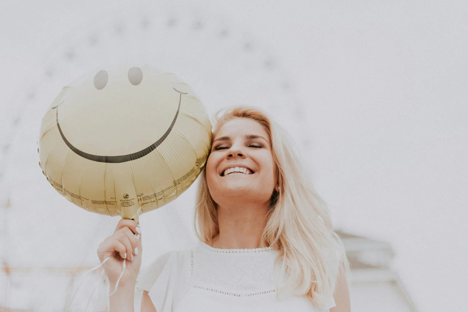 A smiling woman holding a smiley-face balloon