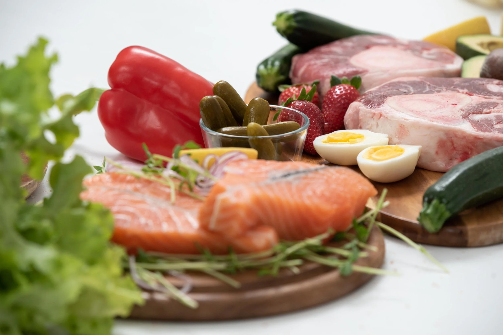 Raw salmon, meats, eggs and vegetables arranged on a wooden board