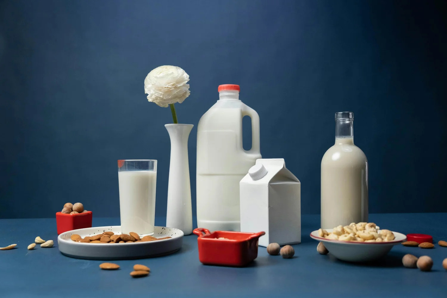 Bottles and cartons of milk with bowls of nuts on a table