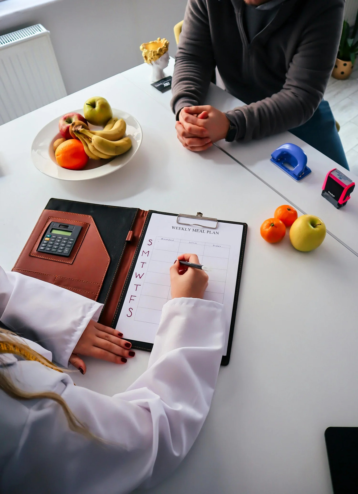 A dietitian taking notes on a clipboard during a consultation