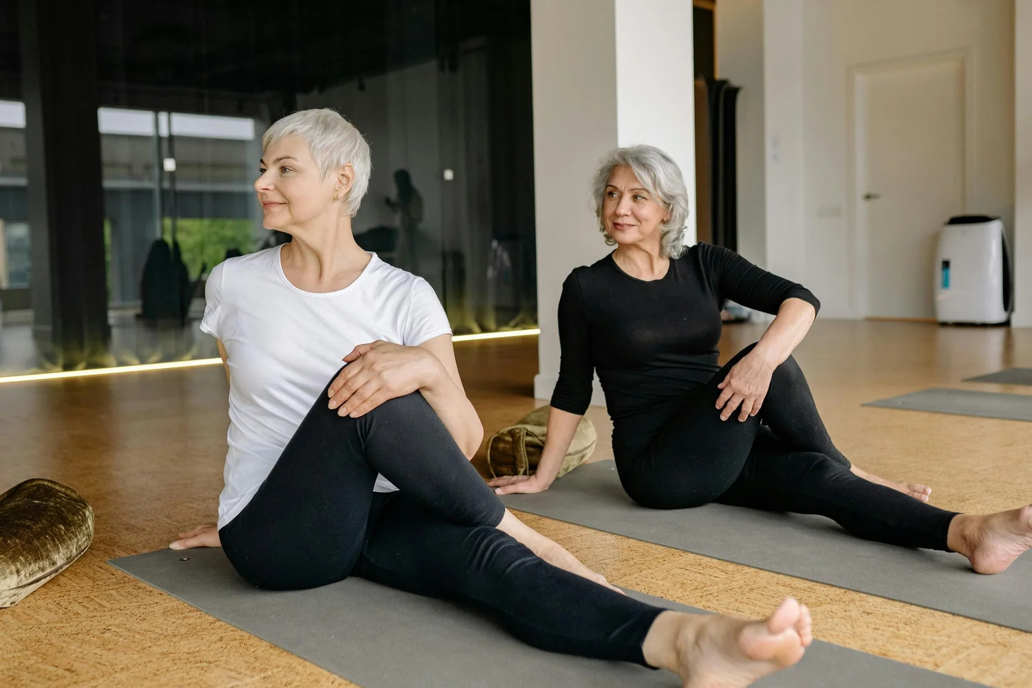 Two women stretching together on yoga mats