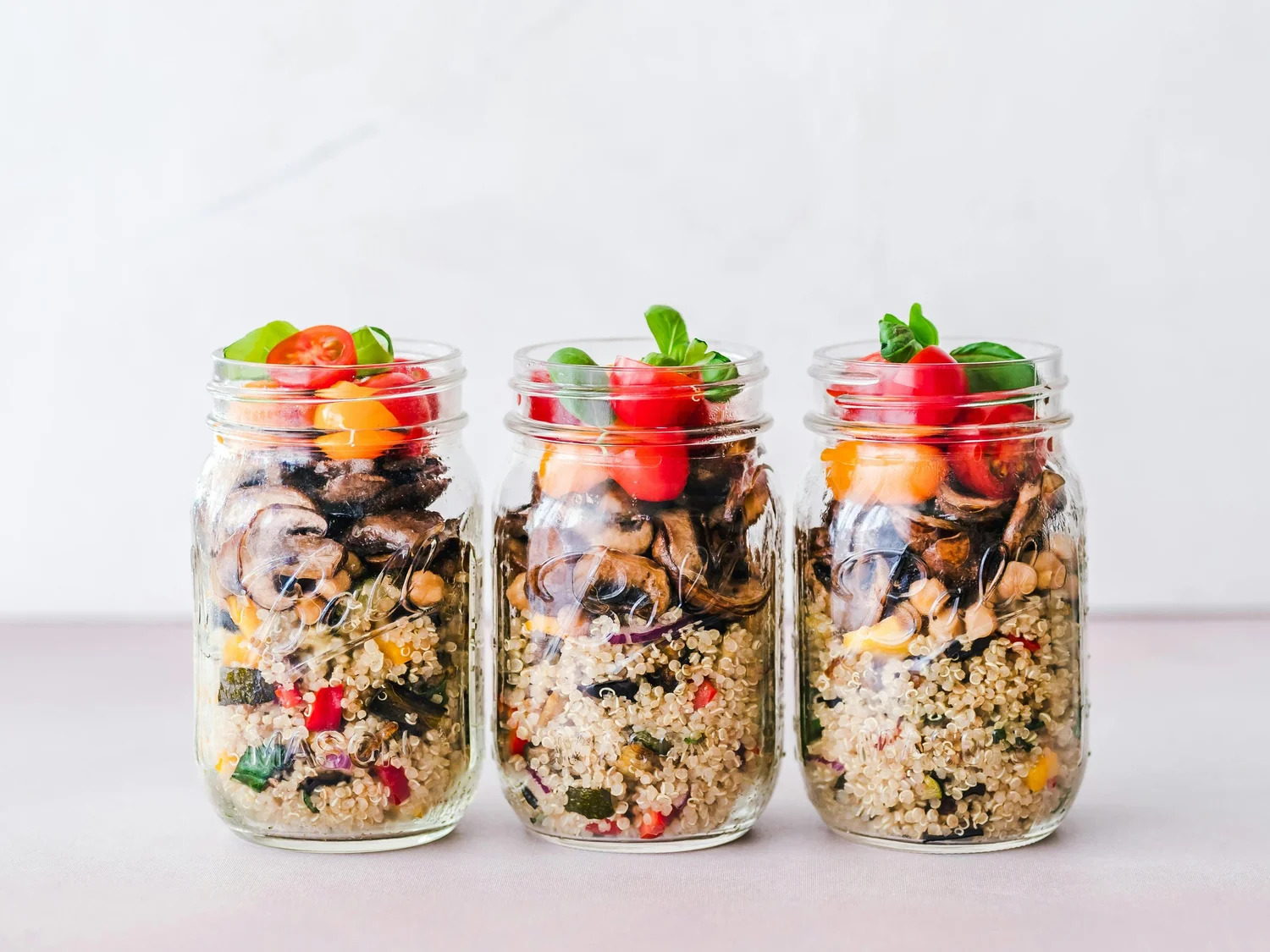 Three jars of layered grain salad with vegetables