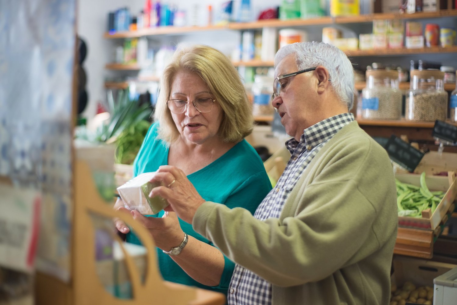 Two older adults reading the label on a package in a grocery store
