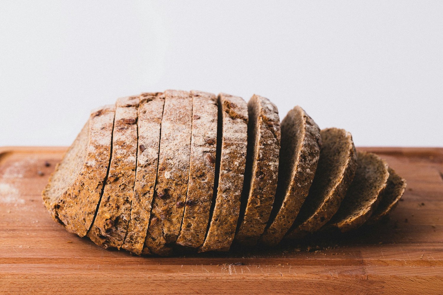 A sliced loaf of seeded whole grain bread on a cutting board