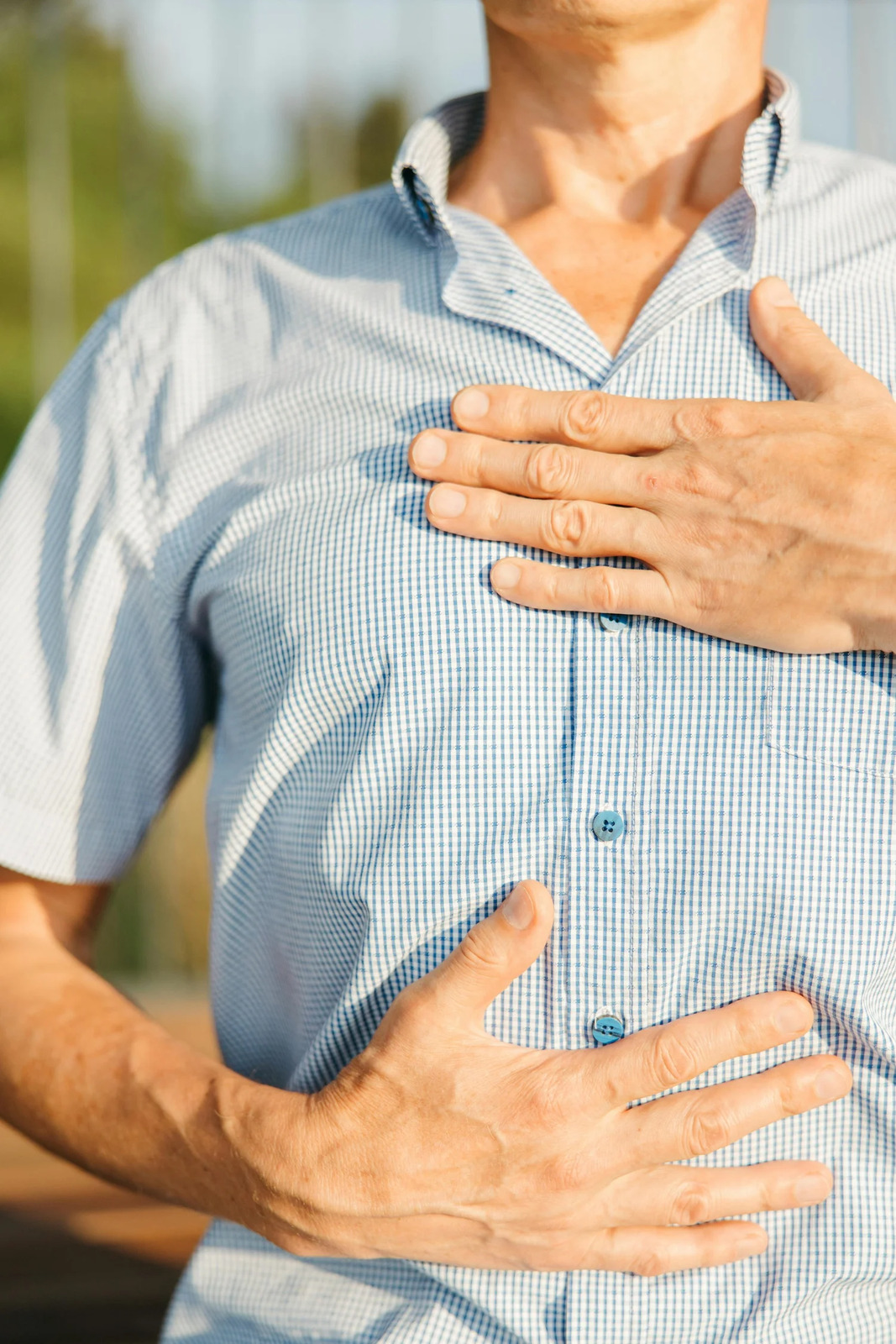 A person pressing one hand to their chest and one to their stomach
