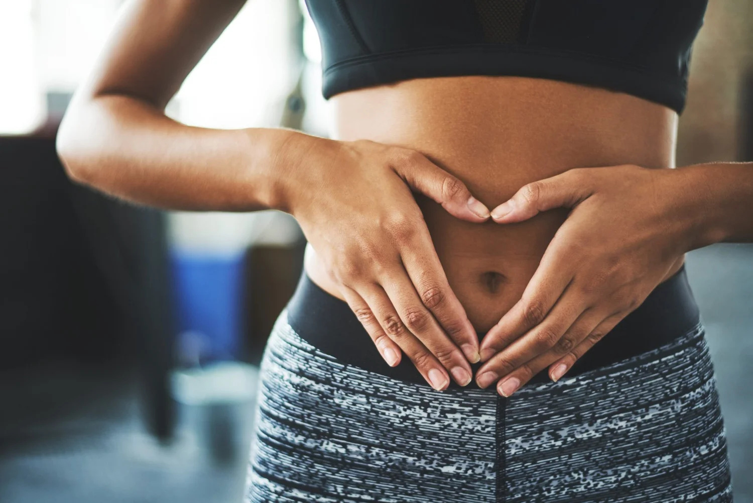 Hands forming a heart shape over a woman's stomach