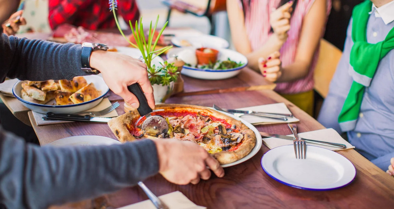 Friends sharing pizza and salad around a table