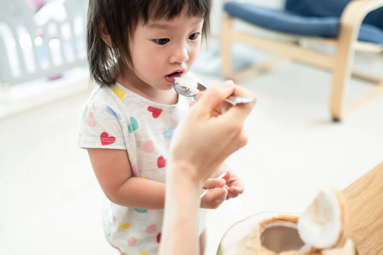 A toddler being fed a spoonful of coconut