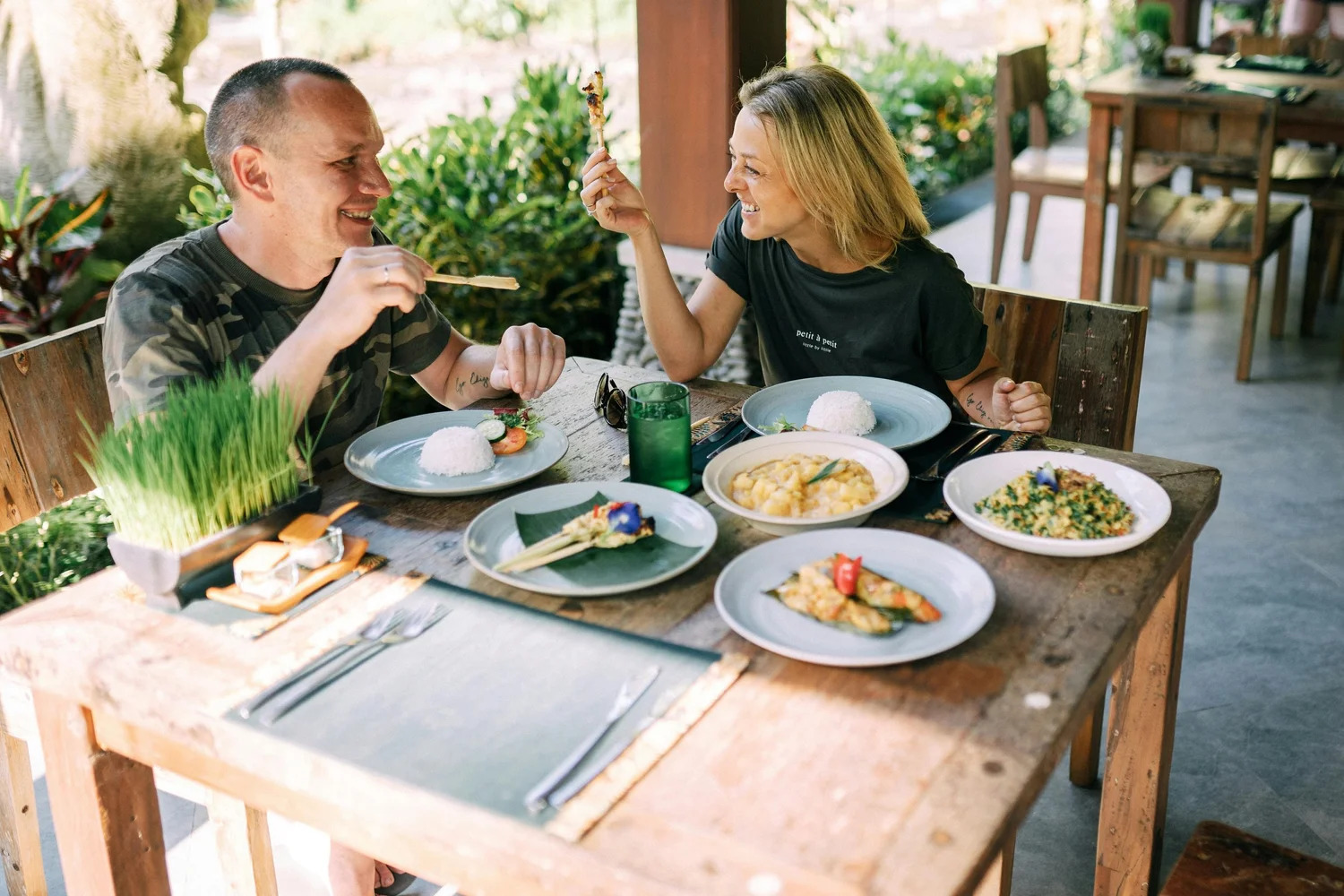 Two friends laughing over a shared meal at an outdoor table