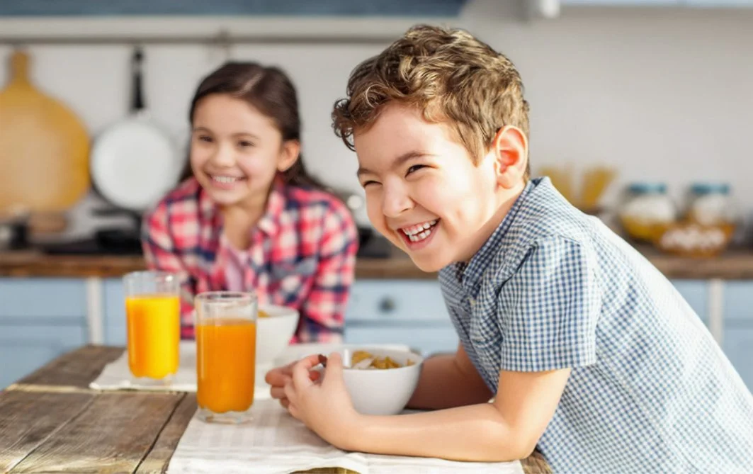 Two children laughing together over breakfast